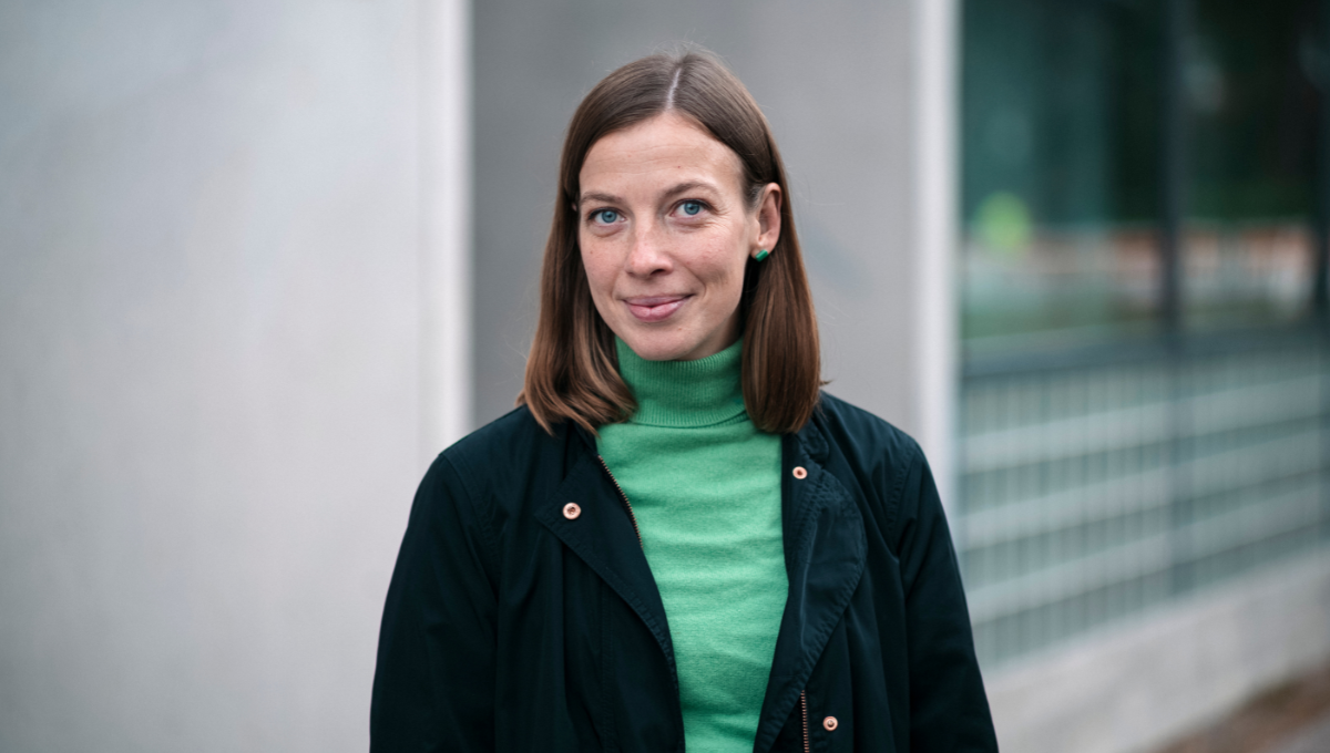 Li Andersson fotograferad inför presidentvalet iklädd en grön polotröja och mörk rock.