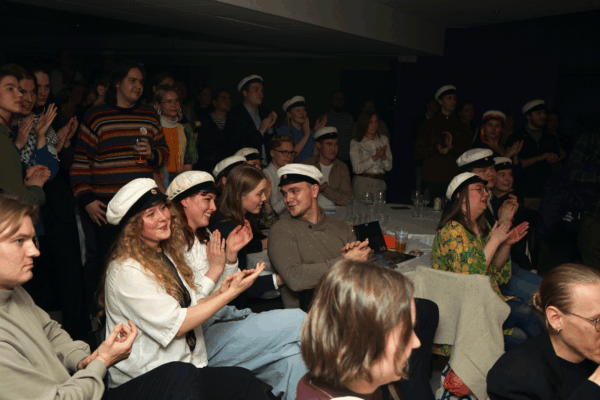 En grupp med personer i studentmössor applåderar och ser glada ut.