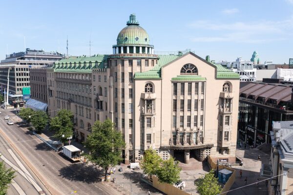 Nya studenthuset i solljus. Väggarna är ljusbeige och taket är ljusgrönt. Byggnaden är hög, med ett torn till vänster. Tornet är något högre än resten av byggnaden.