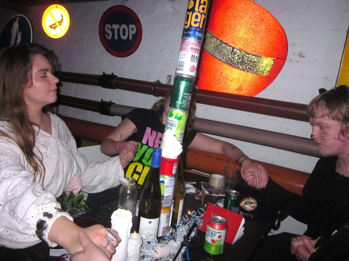 Sitsdeltagare håller varandra i händerna och är vända mot öltornet som de byggt.