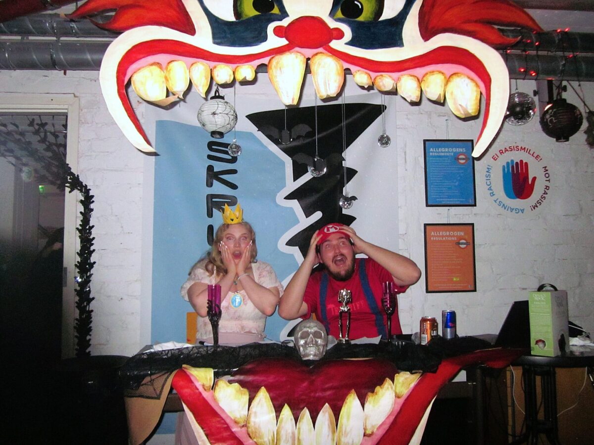 Toastmastrarna Mario och Peach bakom ett målat plakat av en clowns gap.