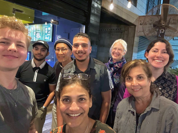 En grupp med människor tar en selfie. De ler alla in i kameran.