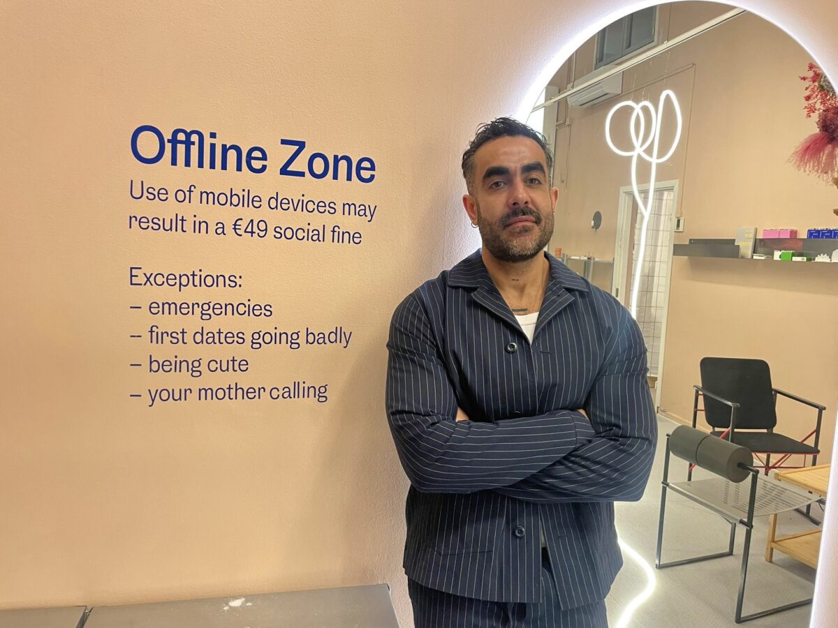Re-offlines grundare Mustafa Alshihani står framför en vägg med texten "Offline Zone. Use of mobile devices may resukt in a 49 euro social fine. Exceptions: emergencies, first dates going badly, being cute, your mother calling."