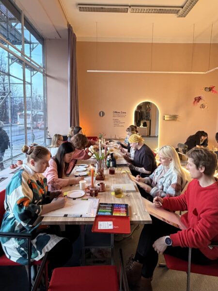 Personer sitter vid ett bord. Bordet är dekorerat med blommor och ljus, och personerna som sitter vid bordet