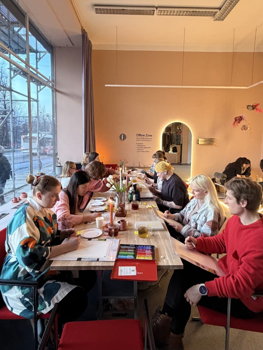 Personer sitter vid ett bord. Bordet är dekorerat med blommor och ljus, och personerna som sitter vid bordet 