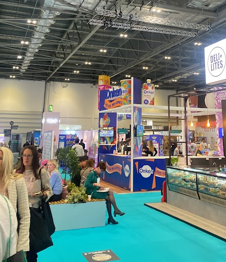 En bild från en mässa. Olika bås med färdigmat.