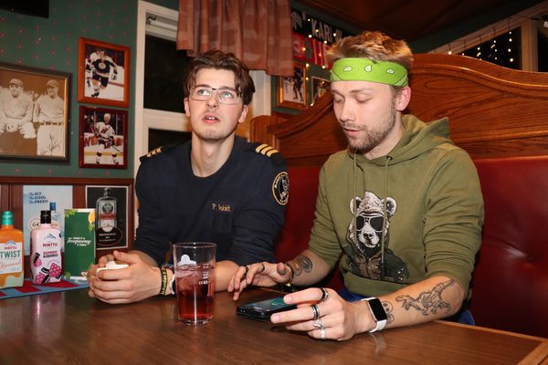 Philipp Woidt och Marcus Andersson sitter i ett bås på en pub. Andersson tittar på sin telefon och Woidt tittar på något bakom kameran.